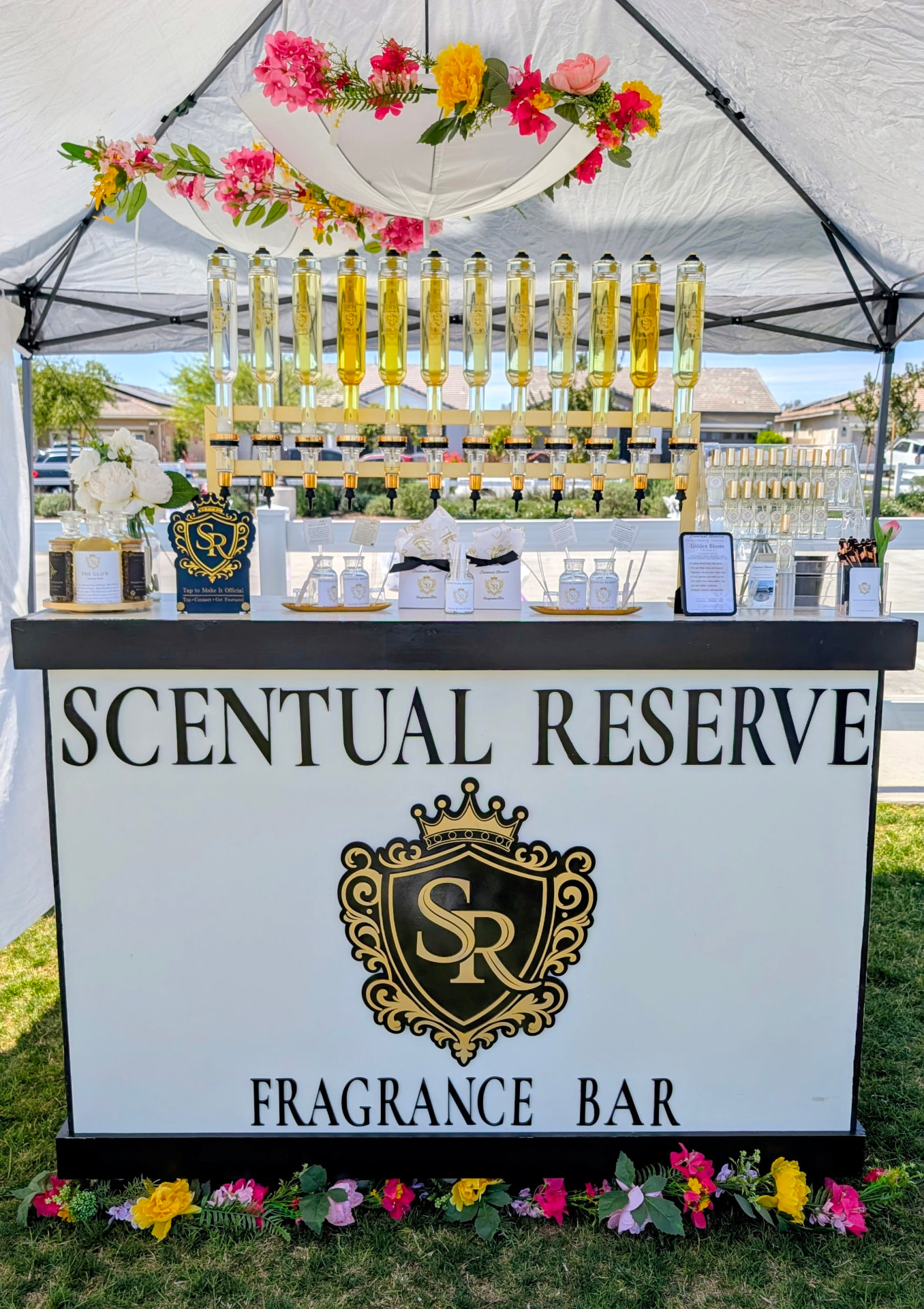 Scentual Reserve bar beneath a floral canopy with gold dispensers