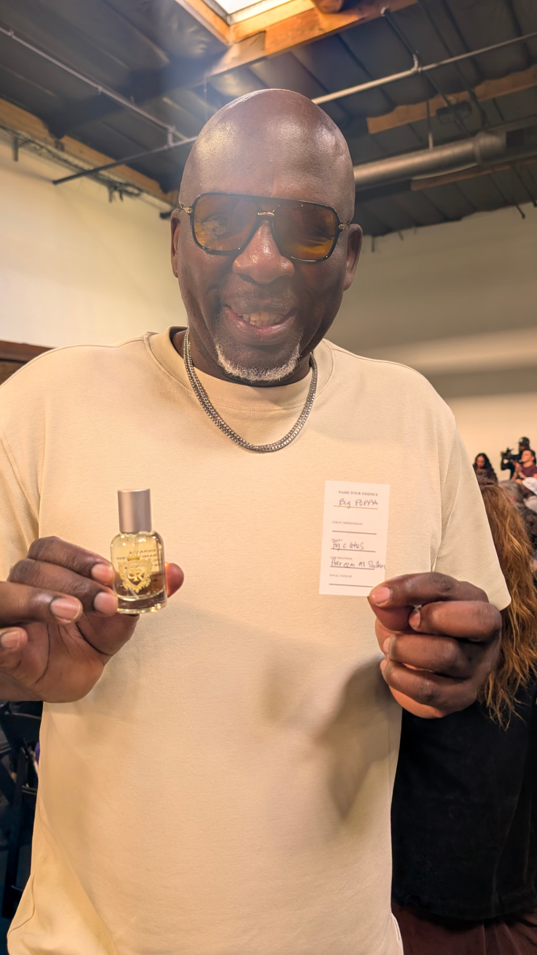A smiling guest holding his personalized fragrance and Name Your Essence card