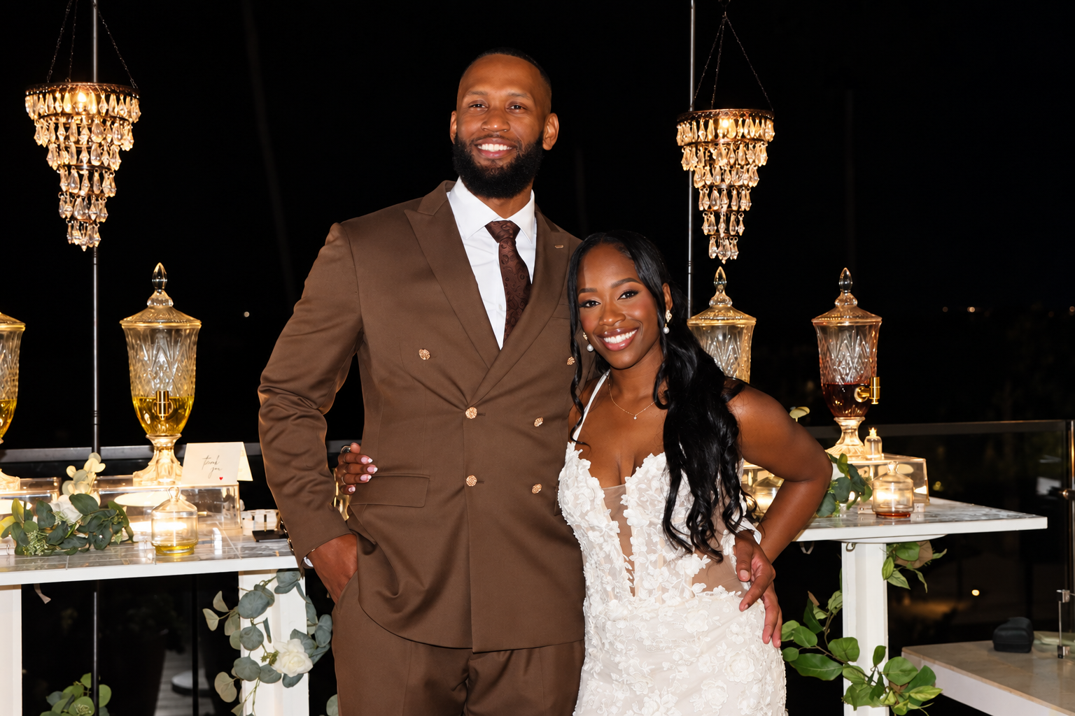 Bride and groom beside the Scentual Reserve fragrance bar and crystal chandeliers at night